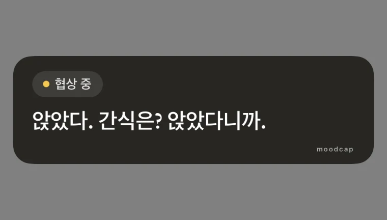 문장 스티커. 어두운 둥근 라벨에 무드 칩 &lsquo;협상 중&rsquo;과 &lsquo;앉았다. 간식은? 앉았다니까.&rsquo;가 적혀 있고, 내 스토리 대신 회색 배경 위에 놓여 있다.